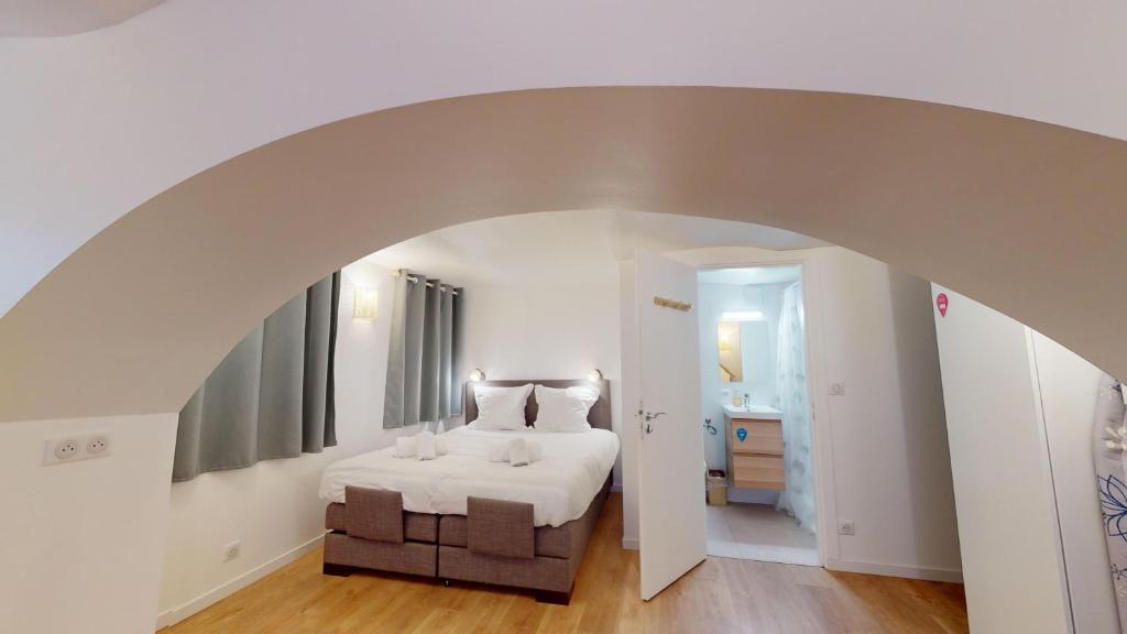 - une chambre avec un lit blanc et une voûte dans l'établissement Studio Castelnau, à Strasbourg