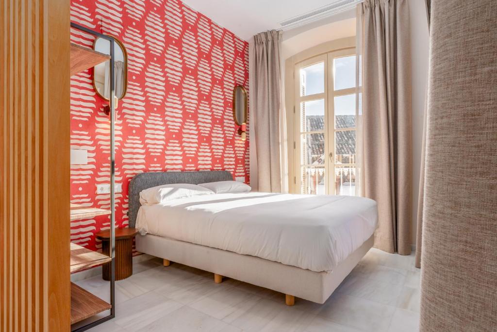 a bedroom with a bed and a red wall at Smartr Malaga Centro in Málaga