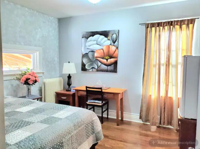 a bedroom with a desk and a bed and a table at Merj's Guest House in Wolesly in Winnipeg