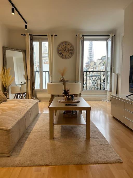 - un salon avec une table et une horloge murale dans l'établissement Appartement Paris vue Tour Eiffel Trocadéro, à Paris