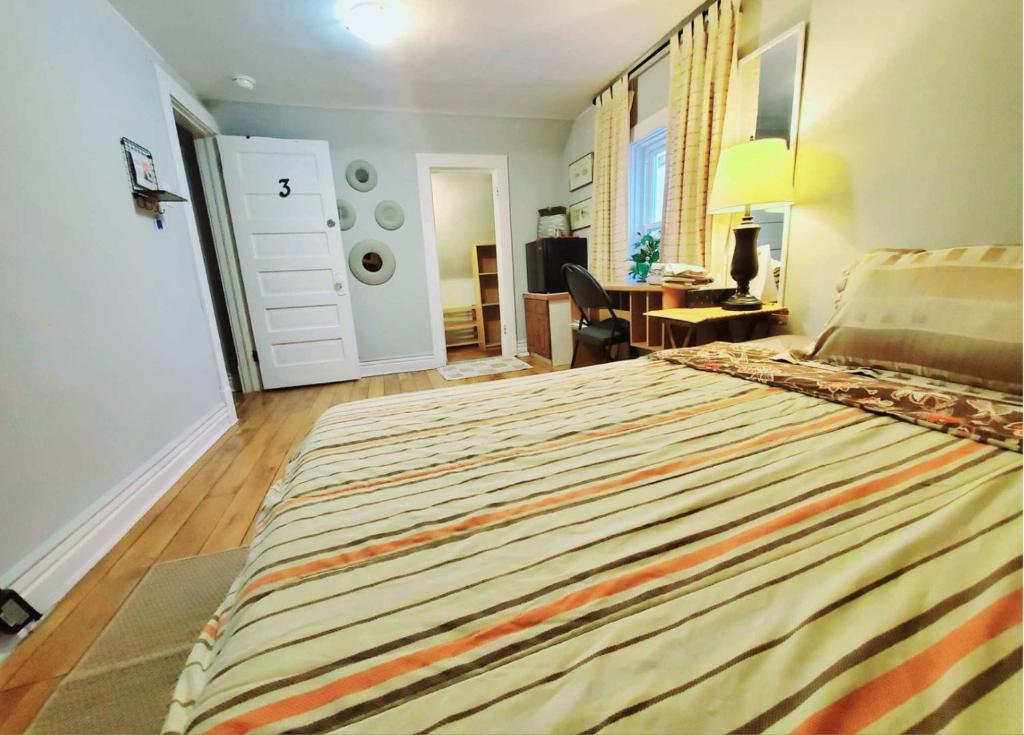 a bedroom with a large bed with a striped bedspread at Merj's Guest House in Wolesly in Winnipeg