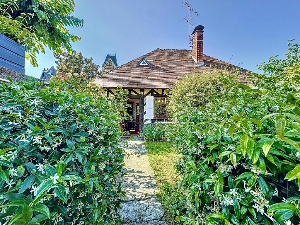 une maison avec une haie devant elle dans l'établissement La pomme bleu, à Deauville