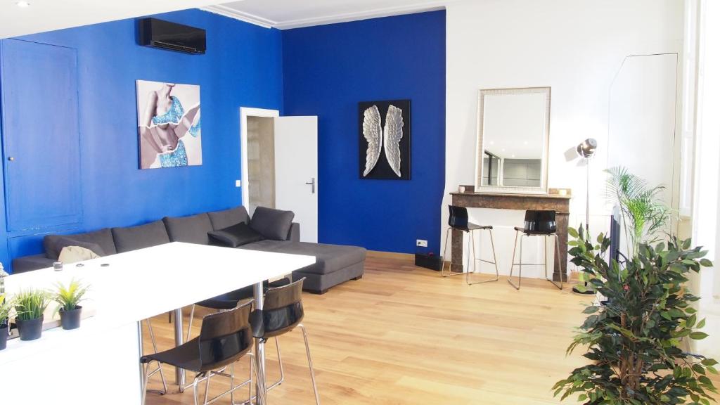 - un salon avec des murs bleus, un canapé et une table dans l'établissement ATYPIQUE Grand théâtre, à Bordeaux