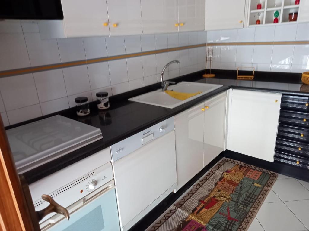 una cucina con mobili bianchi e un lavandino di Savoca Apartment a Giardini Naxos