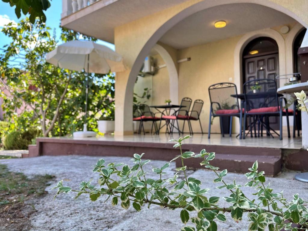 a house with a patio with chairs and an umbrella at Apartments Brebric in Šilo