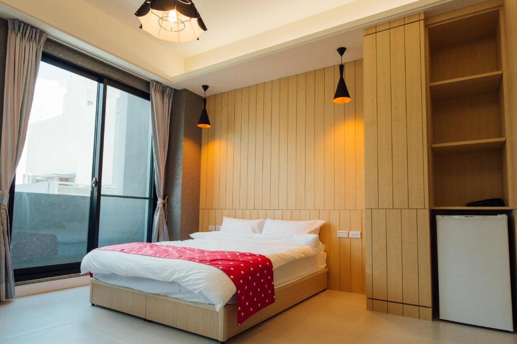 a bedroom with a bed and a large window at Yellow Kite Hostel in Tainan