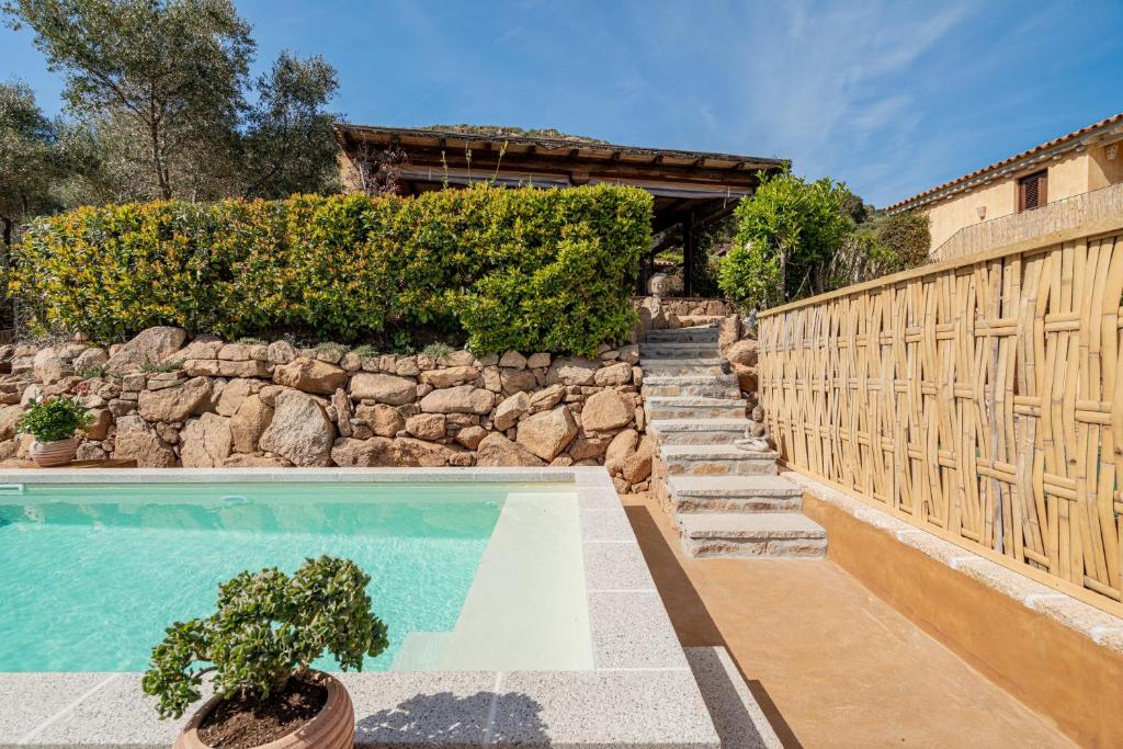 ポルト・サン・パーオロにあるSmart Appart Sweet Country House Sardiniaの石壁と柵のスイミングプール