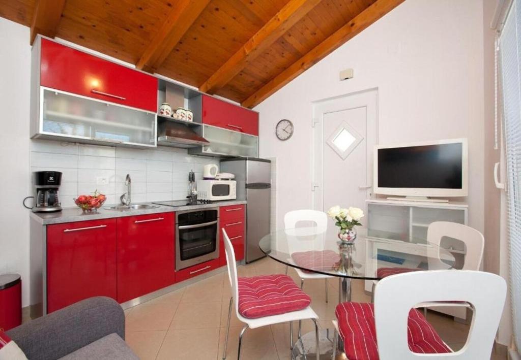 kuchnia z czerwonymi szafkami i stołem z krzesłami w obiekcie Apartments Sora w mieście Preko