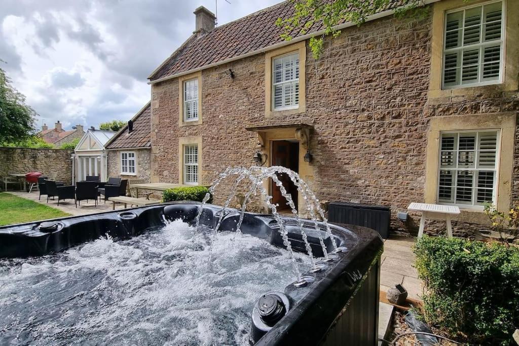 a water fountain in front of a brick house at Wellow Farmhouse in Wellow