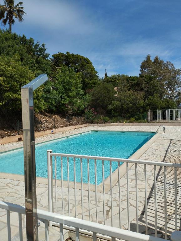 une piscine bleue à côté d'une clôture métallique dans l'établissement Le Bleu Mer, aux Issambres