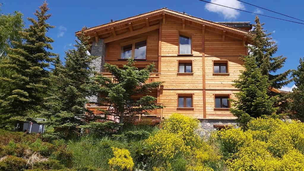 une maison en bois au sommet d'une colline avec des arbres dans l'établissement Prestigious Chalet for 18 Guests, Pool & Jacuzzi, close to slopes and resort center, à Montgenèvre