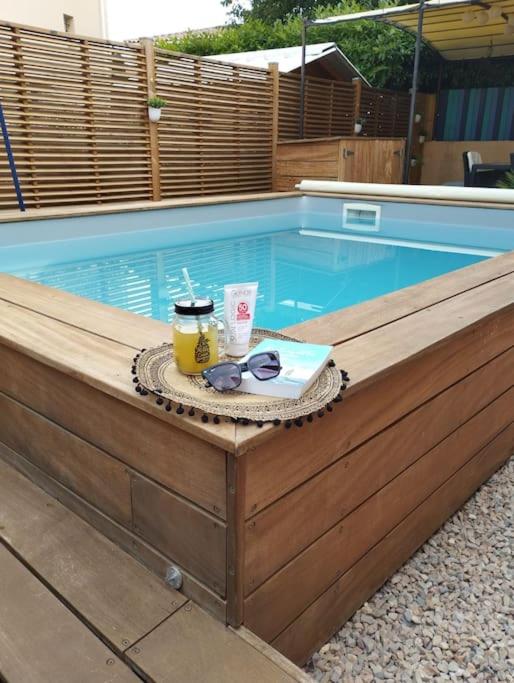 - une piscine avec une table, des lunettes de soleil et une boisson dans l'établissement La Villa Nawengo, au Thor