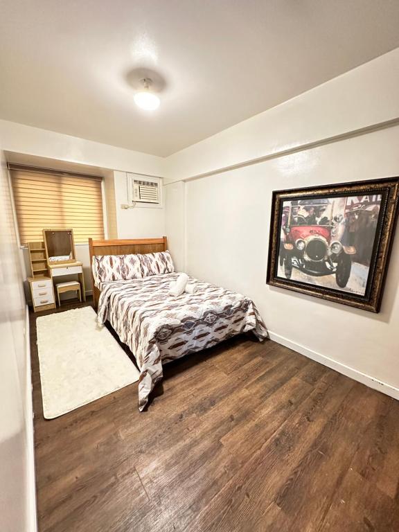 a bedroom with a bed and a painting on the wall at The Haven at Acacia Estates in Manila