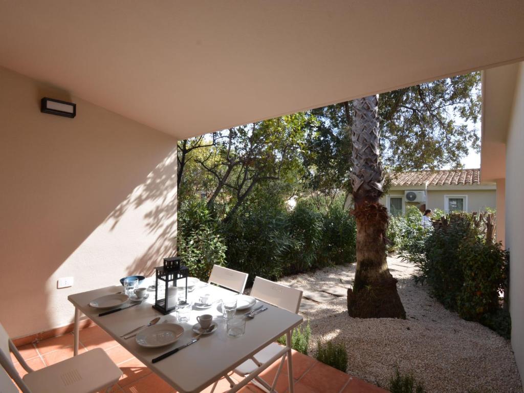 a white table and chairs with a tree in the background at Holiday Home Mirto Marino-2 by Interhome in Costa Rei