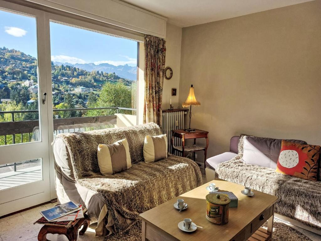un salon avec un canapé et une grande fenêtre dans l'établissement Apartment La côte du Parc-2 by Interhome, à Saint-Gervais-les-Bains