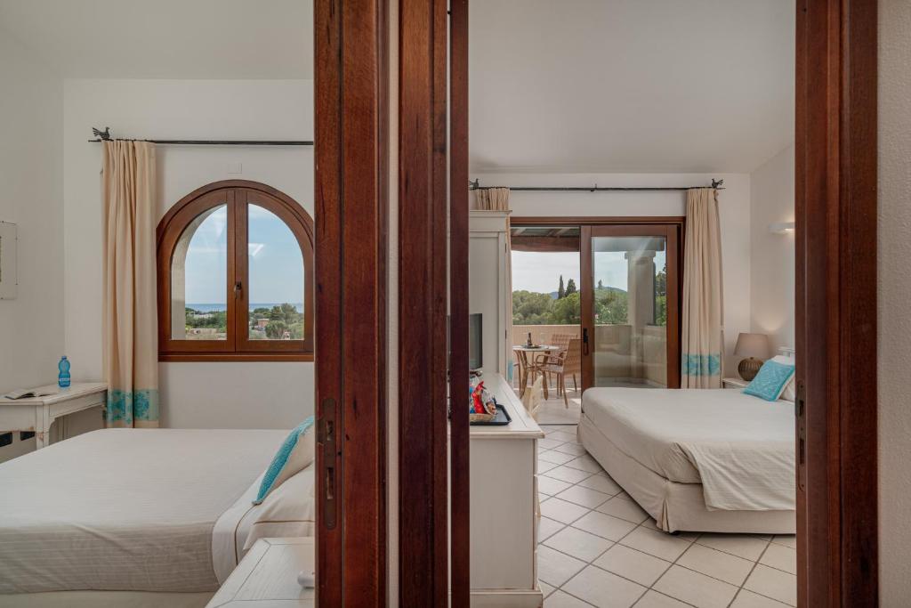 a hotel room with two beds and a balcony at Hotel Mariposas in Villasimius