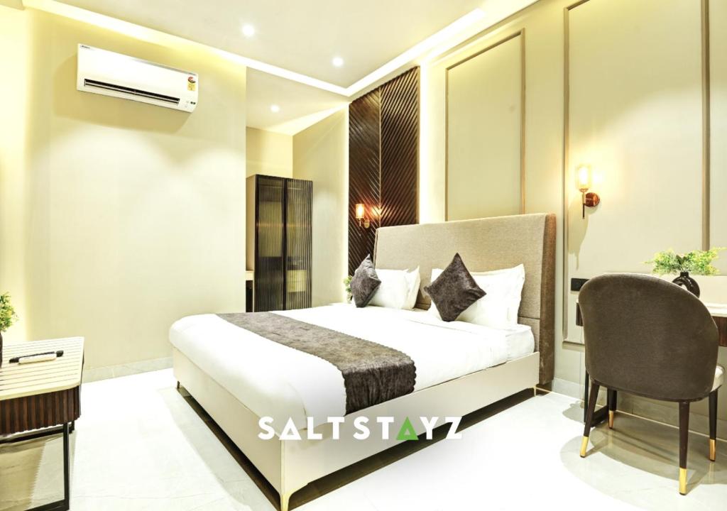 a bedroom with a bed and a desk and a chair at Saltstayz Select - Pitampura in New Delhi