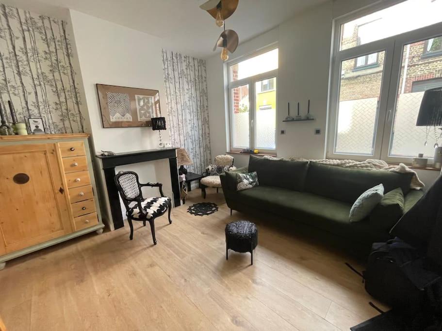 - un salon avec un canapé vert et une cheminée dans l'établissement Malouine de style idéale famille, à Dunkerque