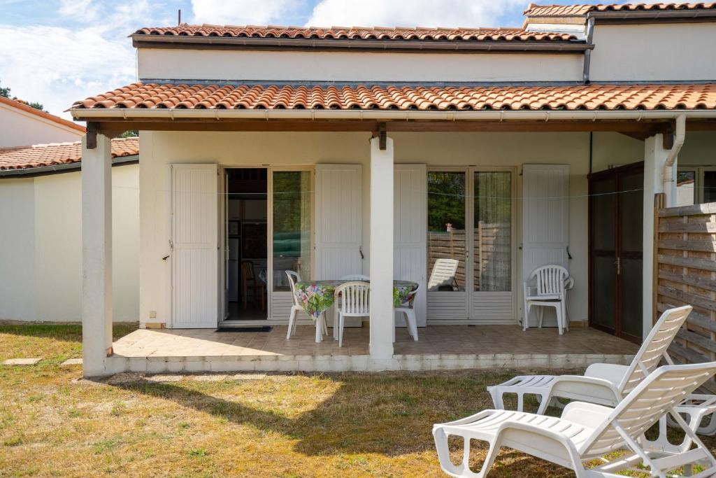 d'une terrasse avec des chaises blanches et une table. dans l'établissement Chaleureuse maison les mouettes, aux Mathes