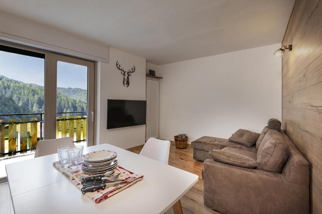 ein Wohnzimmer mit einem weißen Tisch und einem Sofa in der Unterkunft Anni - AffittiPontediLegno in Temù