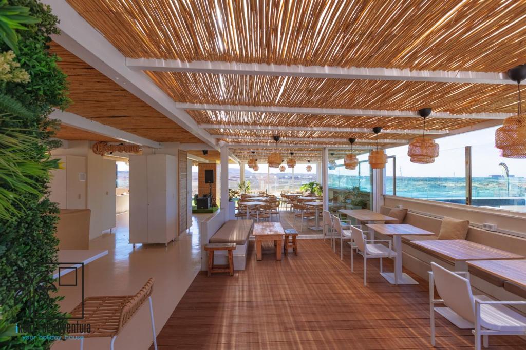 a restaurant with tables and chairs and a view of the ocean at Hola Jag Corralejo Center iRent Fuerteventura in Corralejo