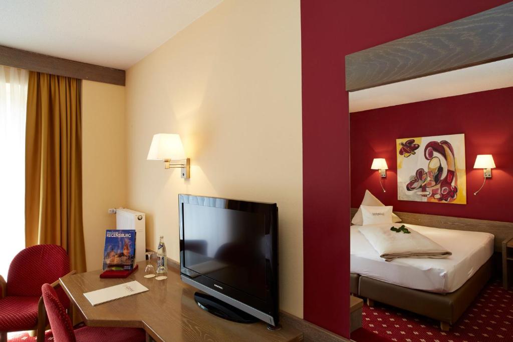 a hotel room with a bed and a flat screen tv at Garden & SPA Hotel Das Götzfried in Regensburg