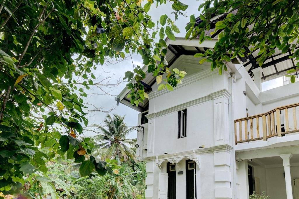 a white house with a balcony and trees at Watu House in Dickwella