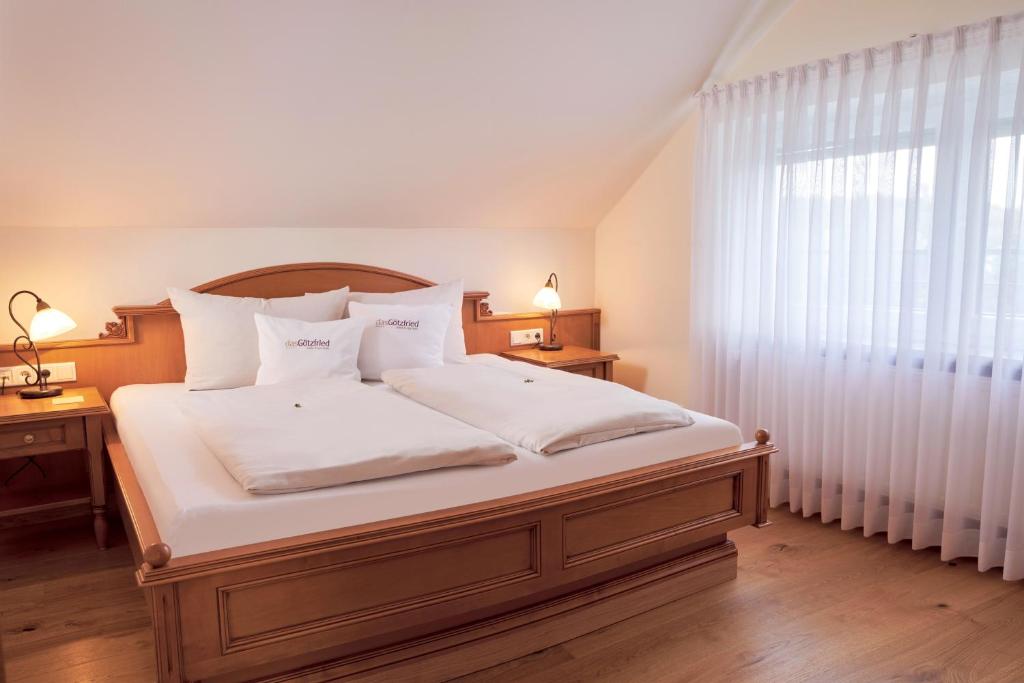 a bedroom with a bed with white sheets and a window at Garden & SPA Hotel Das Götzfried in Regensburg