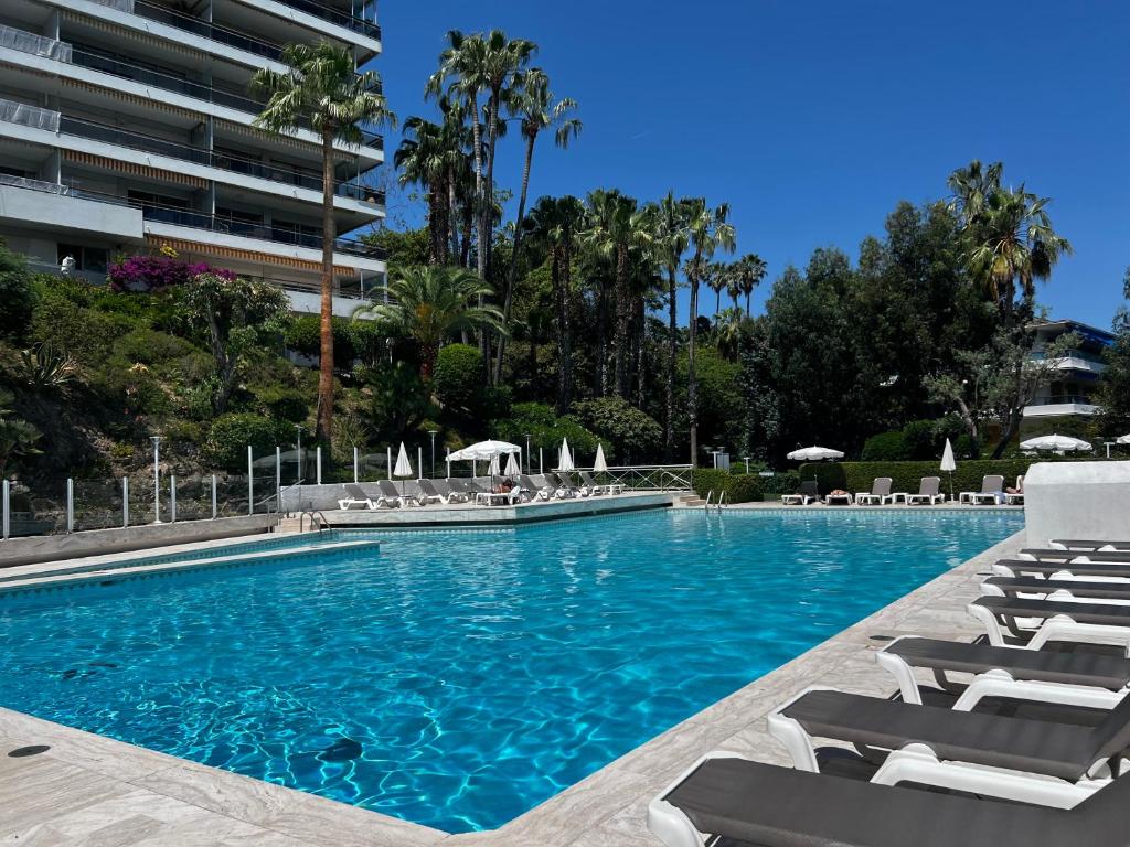 une piscine avec des chaises longues et un bâtiment dans l'établissement CHARMANT STUDIO AVEC PISCINE à LA MIRANDOLE, à Vallauris