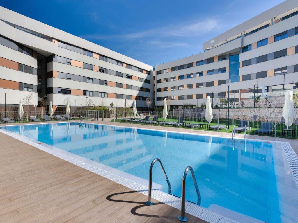 a large swimming pool in front of a building at Livensa Living Studios Madrid Alcobendas in Alcobendas