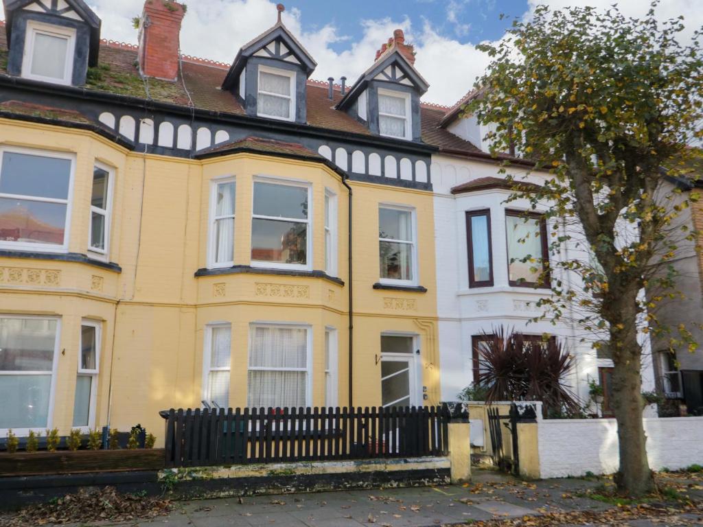 a yellow house with a black fence in front of it at Bodafon View in Llandudno