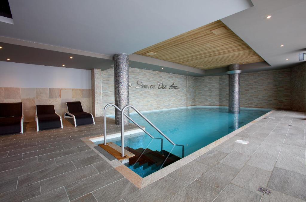 - une piscine dans le hall avec des chaises dans l'établissement Chalet des Neiges -La Source des Arcs, à Arc 2000