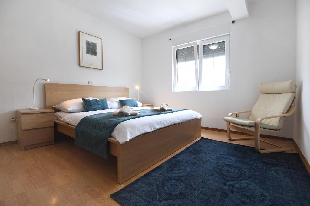 a bedroom with a bed and a chair in it at Bibinje Apartments in Bibinje