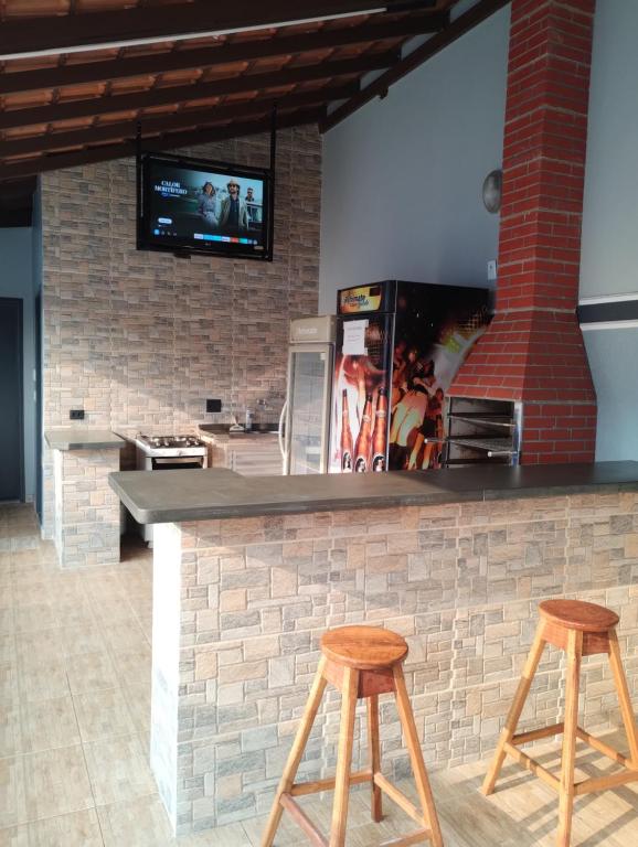 um bar com dois bancos e uma televisão numa parede de tijolos em Casa com piscina em Ribeirão Preto