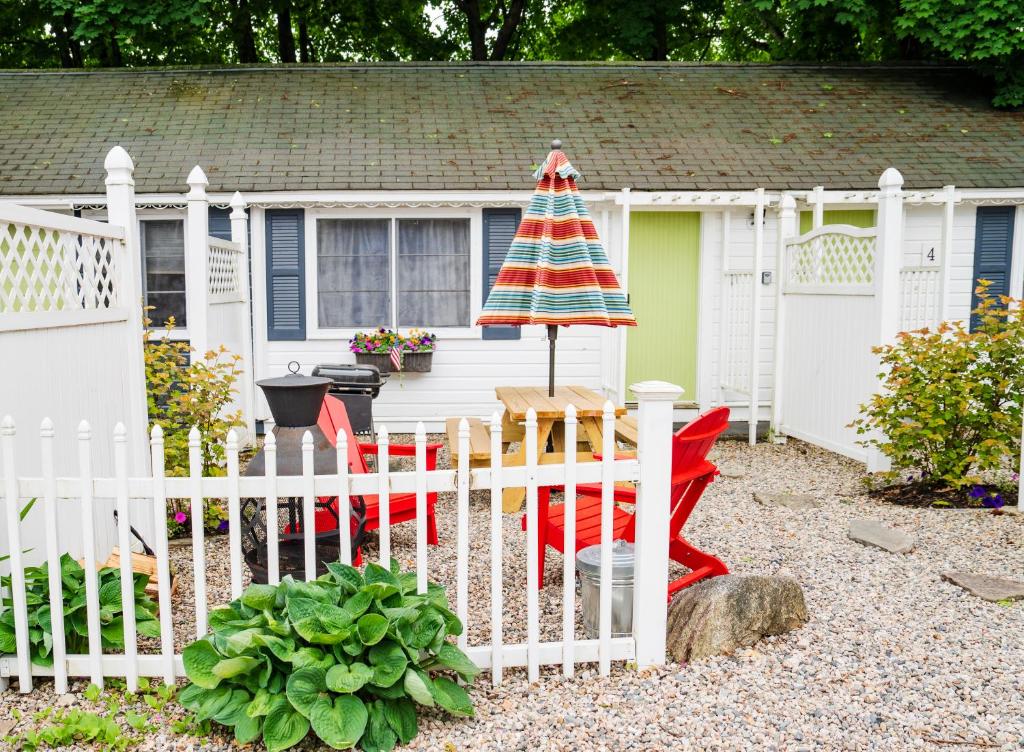 une clôture blanche devant une maison avec un parapluie dans l'établissement Cottage 3 - Pet Friendly - 1 Bedroom / 1 Bath, à Wolfeboro