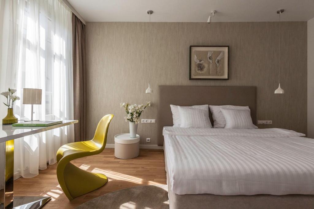 1 dormitorio con 1 cama y 1 silla amarilla en Casati Hotel - Adults Only, en Budapest