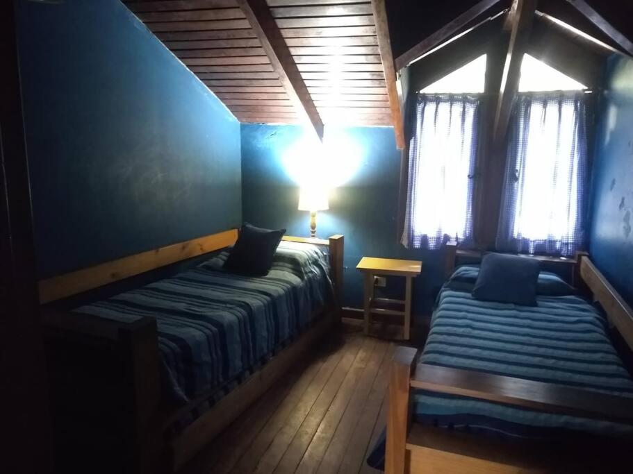 1 dormitorio con 2 camas, lámpara y ventanas en casa de campo temporario, en Yala