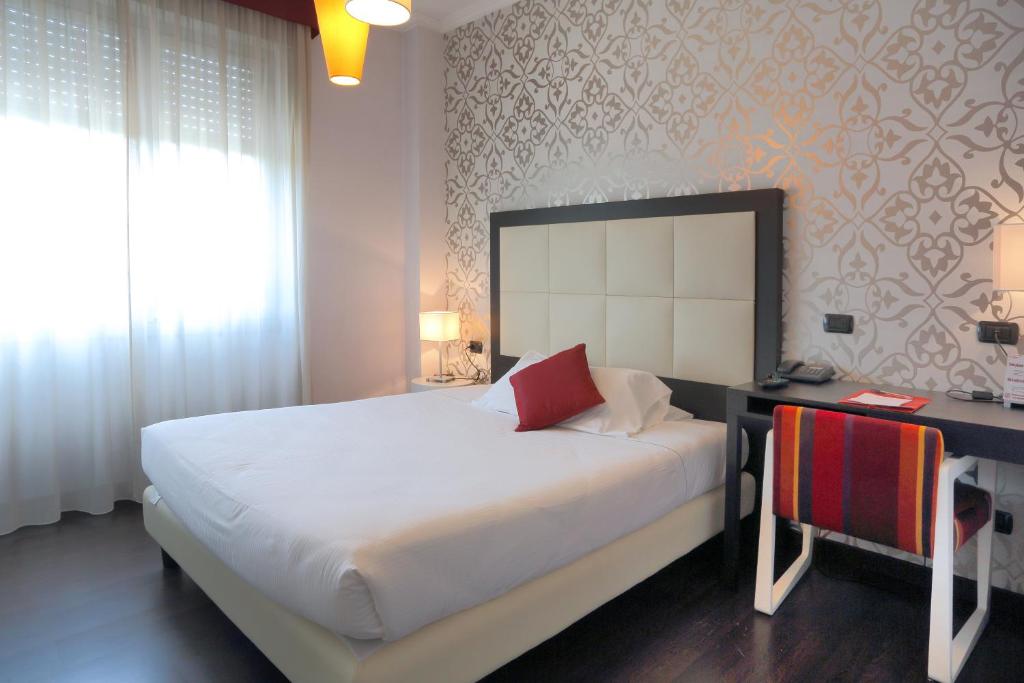 a bedroom with a large bed with a desk and a window at Hotel La Torretta in Bollate