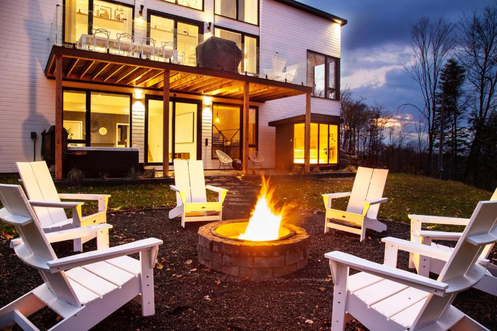 a group of chairs around a fire pit in front of a house at Chalet Peak Tremblant: Your Mountain Escape. in La Conception