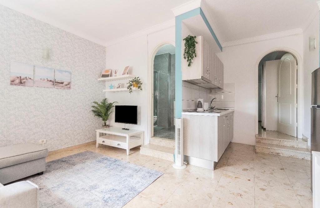 a white living room with a television and a kitchen at Lovely Apartament Taidia in Maspalomas