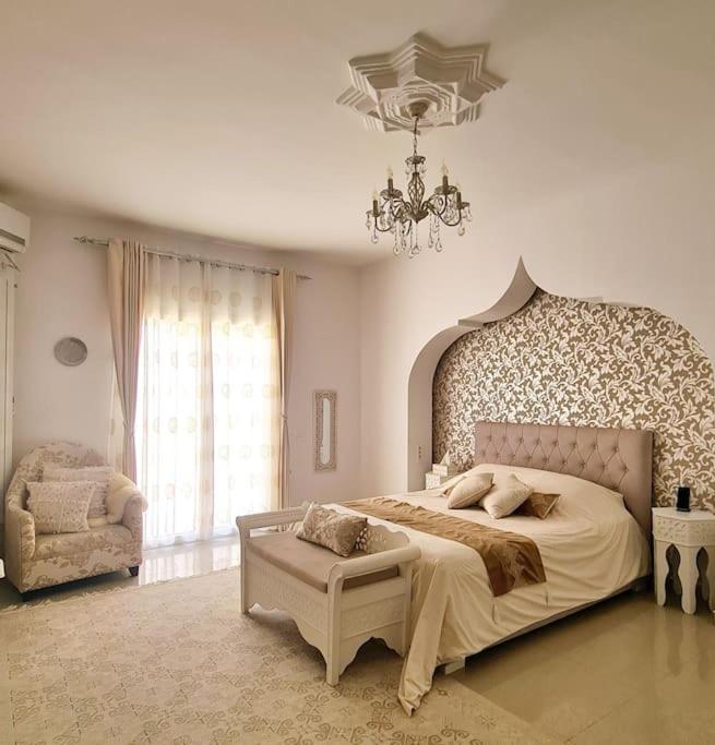 a bedroom with a large bed and a chandelier at Villa Romana Monastir in Monastir
