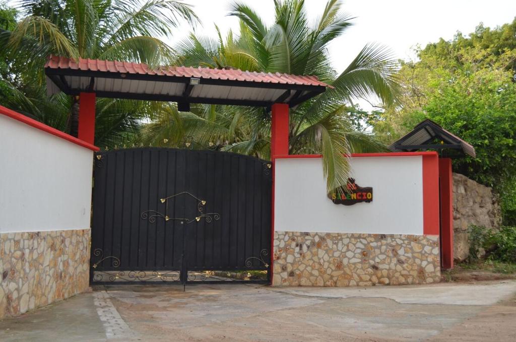 a black and red gate with a palm tree behind it at Casa Campestre El Silencio con Familias Exitosas in Rivera