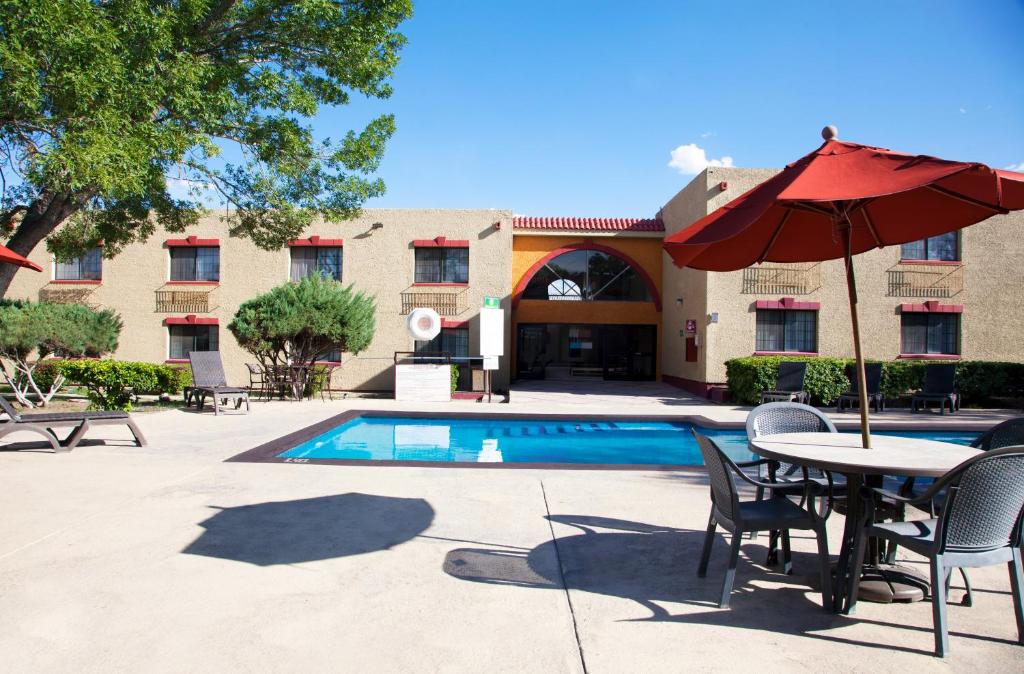 Un patio con mesa y sombrilla junto a una piscina. en Casa Grande Chihuahua, en Chihuahua