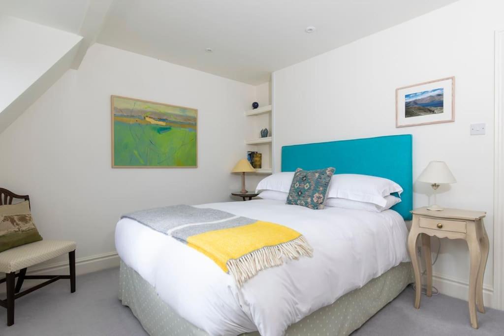 a bedroom with a large bed and a chair at Cotswold Stable Cottage in Bibury