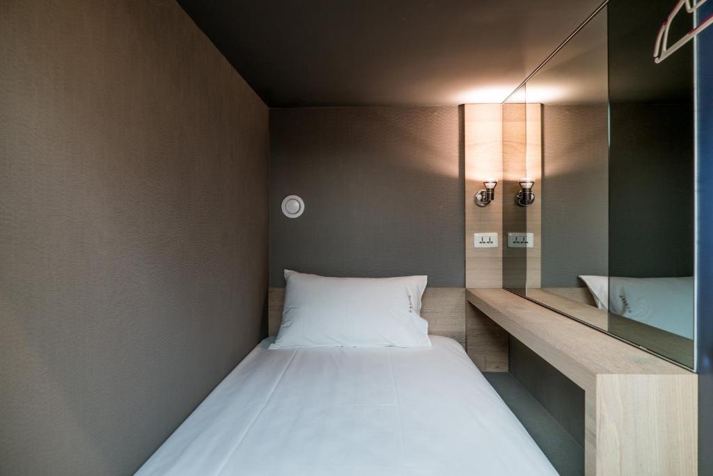 a small room with a bed and a mirror at Taipei Discover Hostel in Taipei