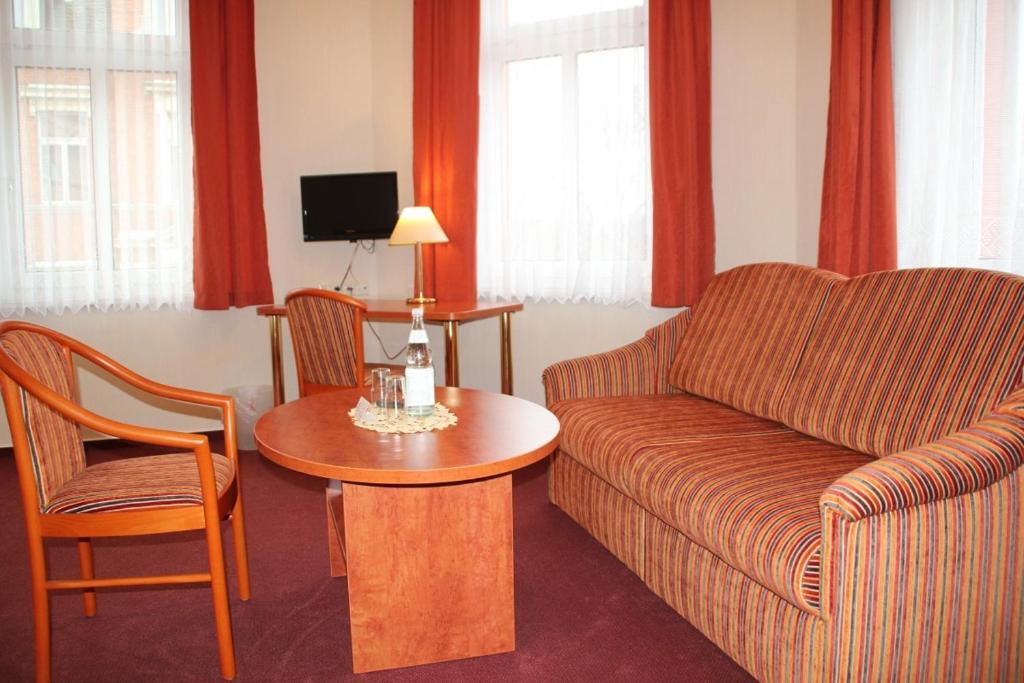 a living room with a couch and a table and chairs at Hotel Thüringer Hof in Rudolstadt