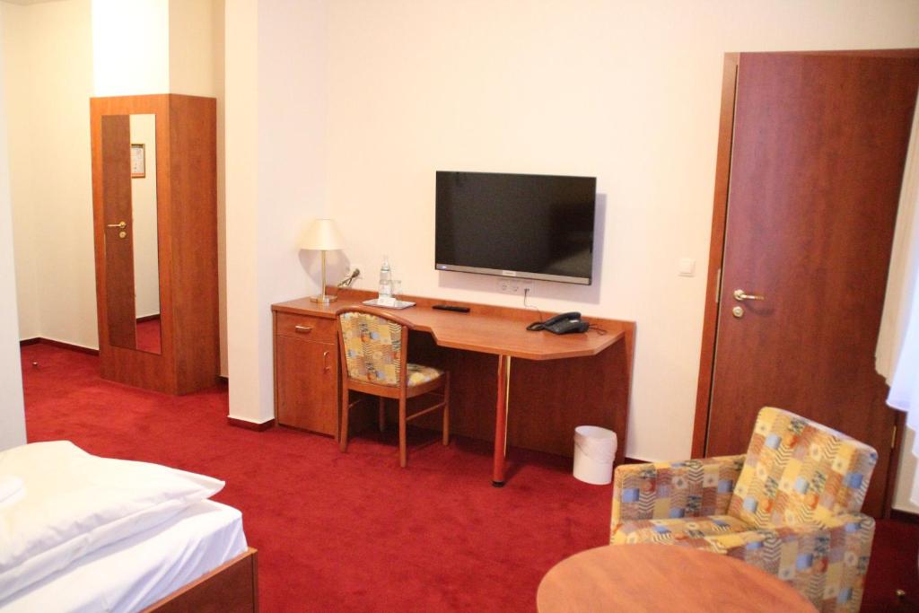 a hotel room with a desk with a television and a bed at Hotel Thüringer Hof in Rudolstadt