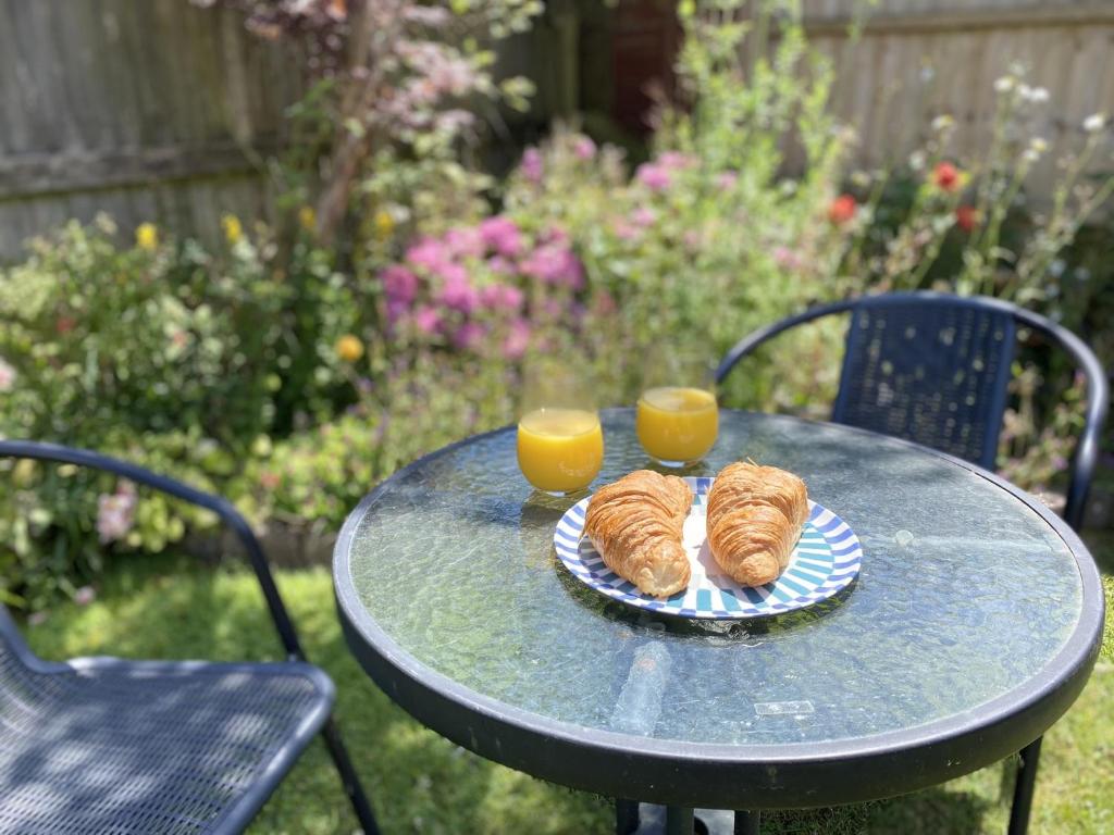 twee gebakjes op een tafel met twee kopjes sinaasappelsap bij Daisy Cottage by NewFo rest in Lymington