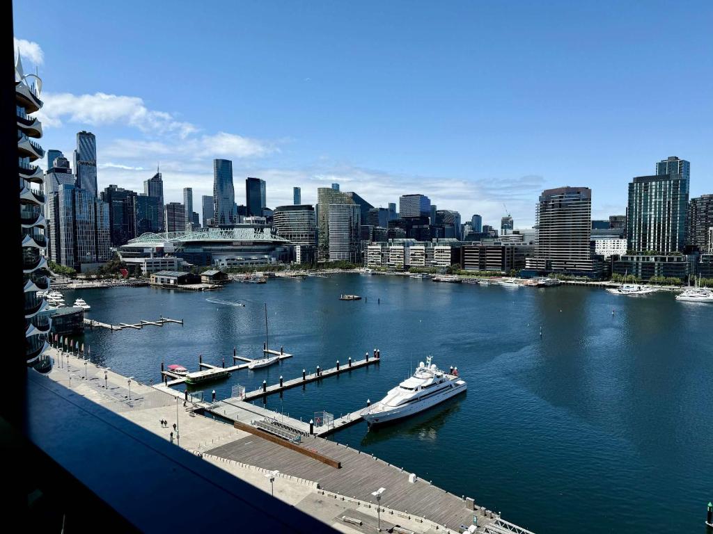 a boat docked at a dock in a river with a city at Marina Tower - Stunning Harbour & City View in Melbourne