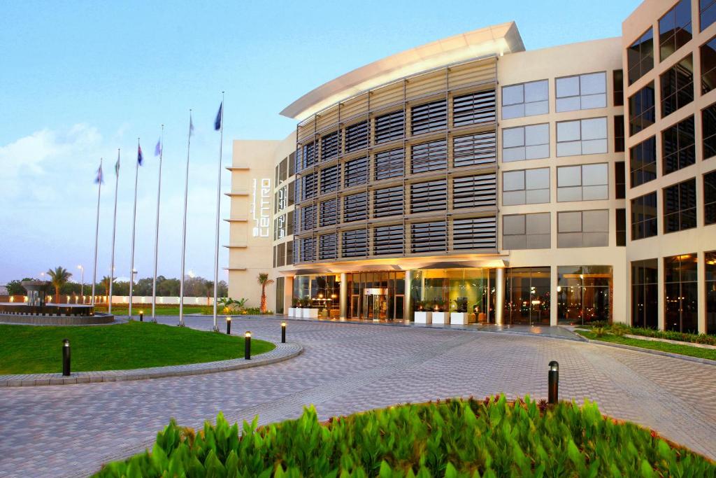 un grand bâtiment avec drapeaux devant lui dans l'établissement Centro Sharjah, à Charjah